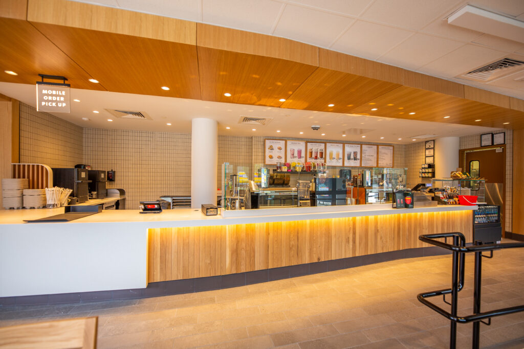 Starbucks counter with wood paneling on the front and on the ceiling.